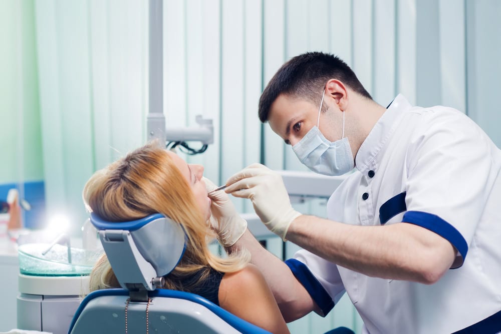 Dentist performs a dental check up on a woman: health insurance comparison